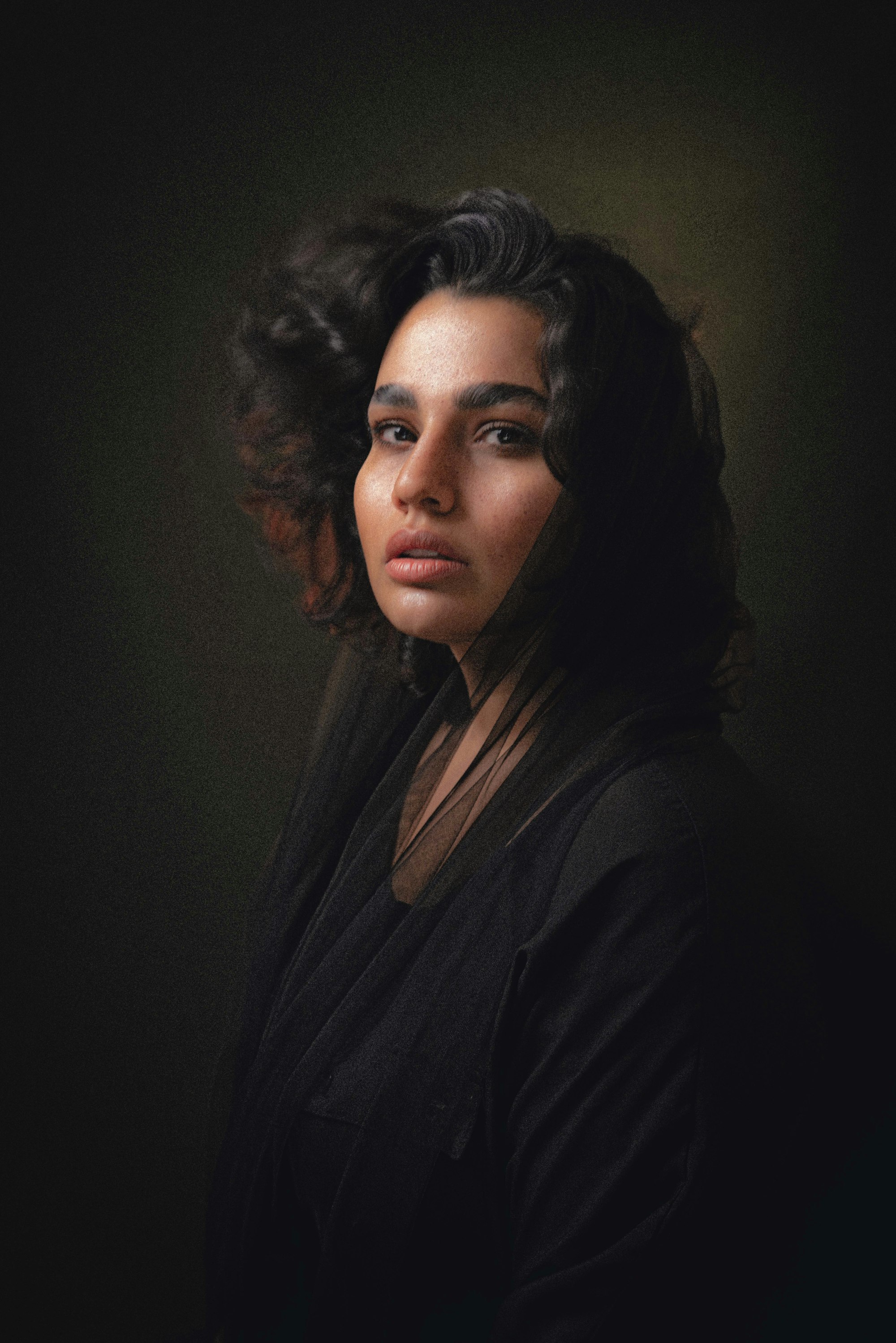 Portrait of a woman with dark, voluminous curls in low light