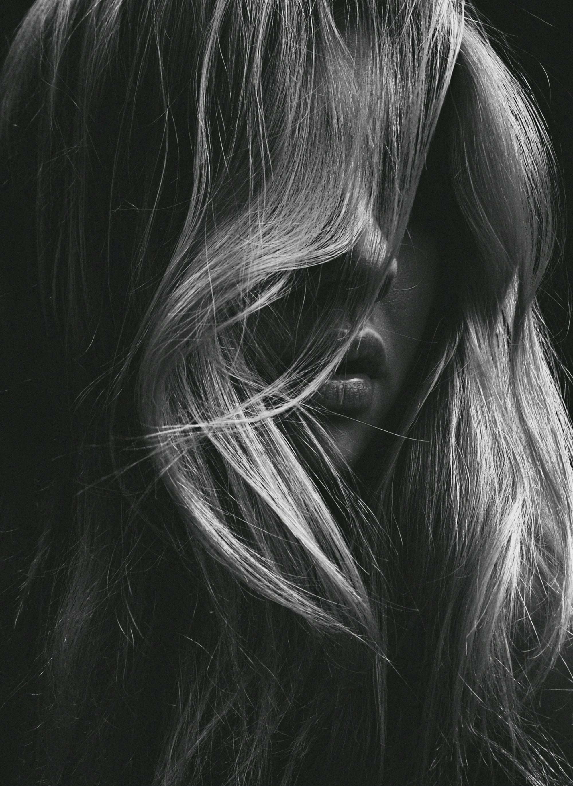 Close-up black and white detail of strands of glossy hair across a face
