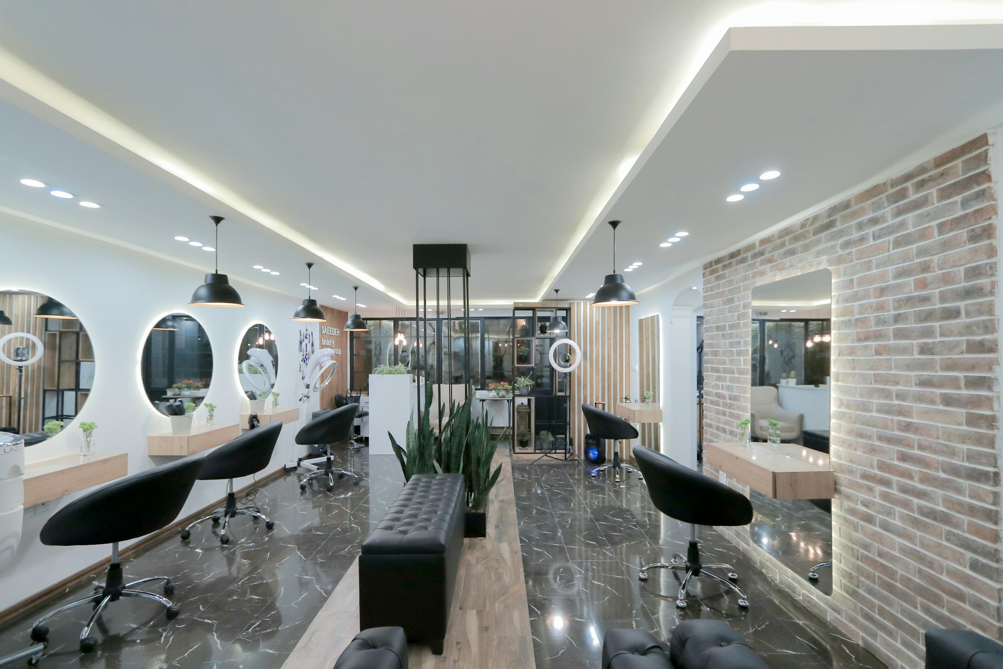 A bright, modern hair salon interior with styling stations, round mirrors and plants